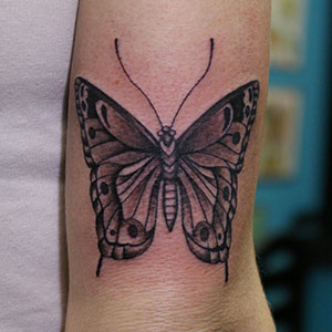 上腕の後ろ側への蝶のタトゥー